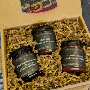 three jars of jam in a kraft paper box with crinkle paper and a holographic sticker that says Top Shelf Preserves